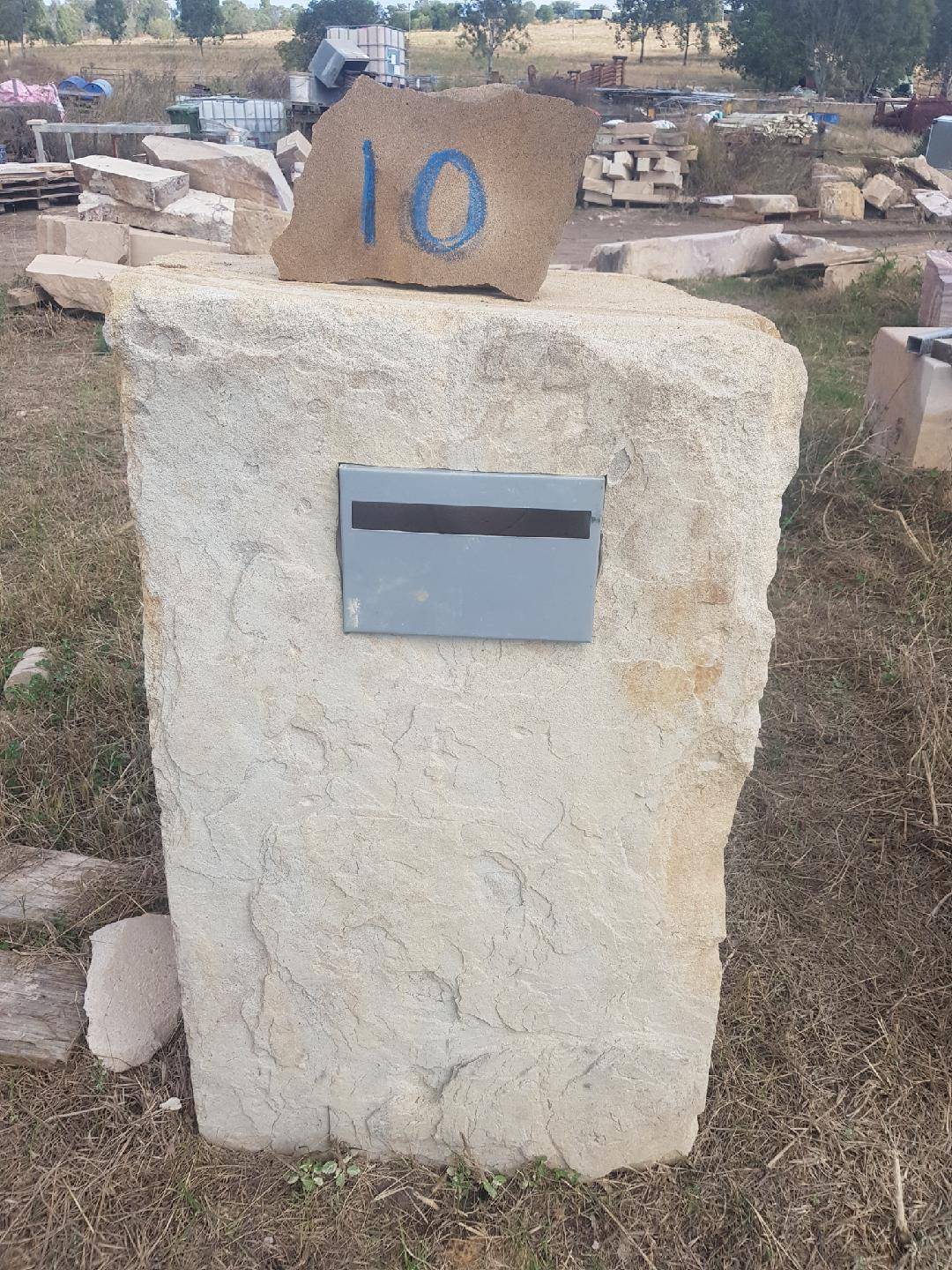 Rustic sandstone letterbox installed in garden setting